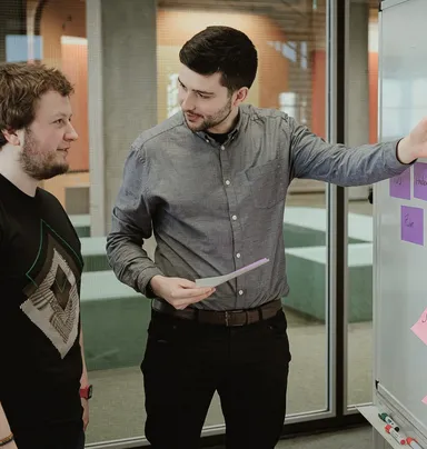 Alex zeigt Hannes im Pair-Programming seinen aktuellen Stand.